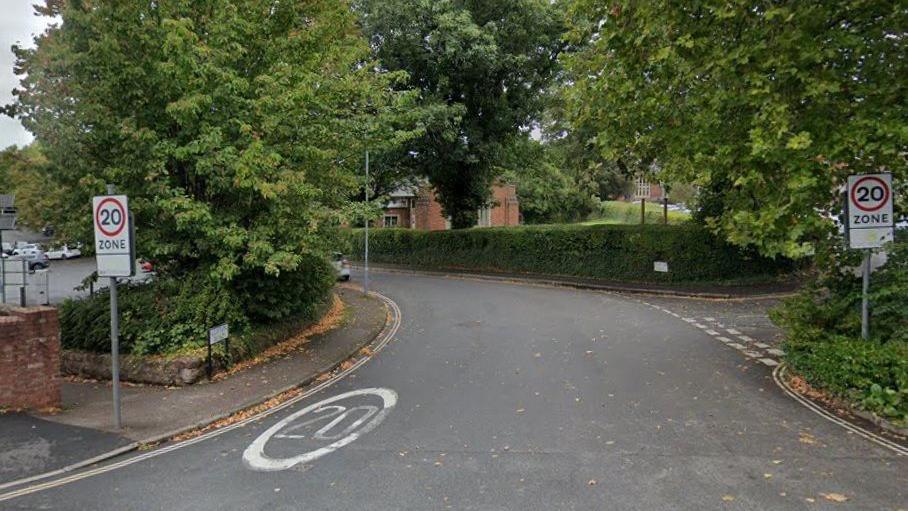 A street view image of Clifton Road in Exeter. It has 20mph signs and writing on the road.