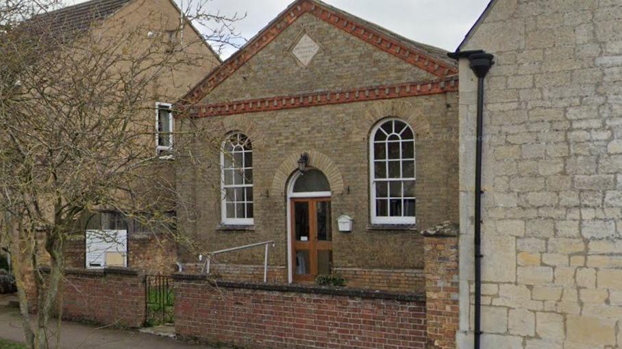 Exterior image of the Church building - with a triangle roof  and white oval glass windows with white frames.