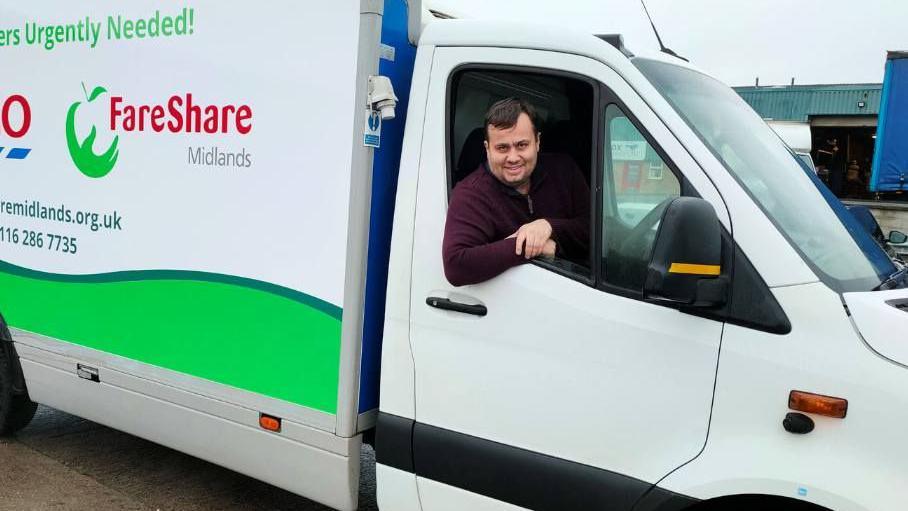 A man in the driver's seat of a Fareshare Midlands white van