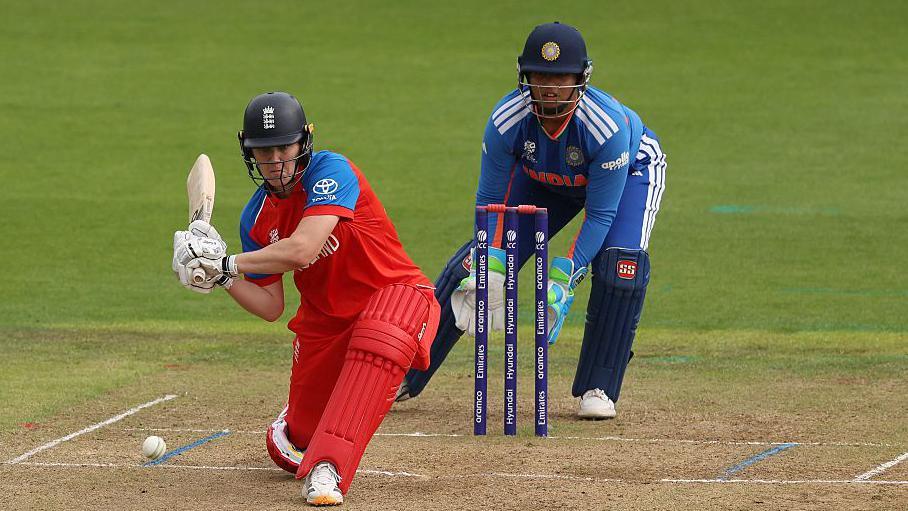 Nat Sciver-Brunt plays a sweep shot as India wicketkeeper Richa Ghosh watches on