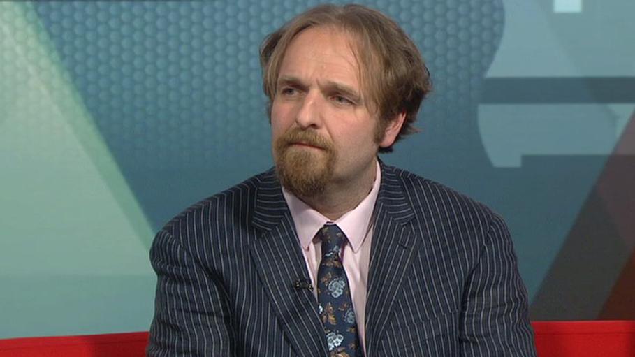 Robert Alden is the councillor for Erdington and leads the Birmingham Conservatives. He is wearing a stripy jacket, pink shirt and a blue, funky tie. He has medium-length hair and a goatee.