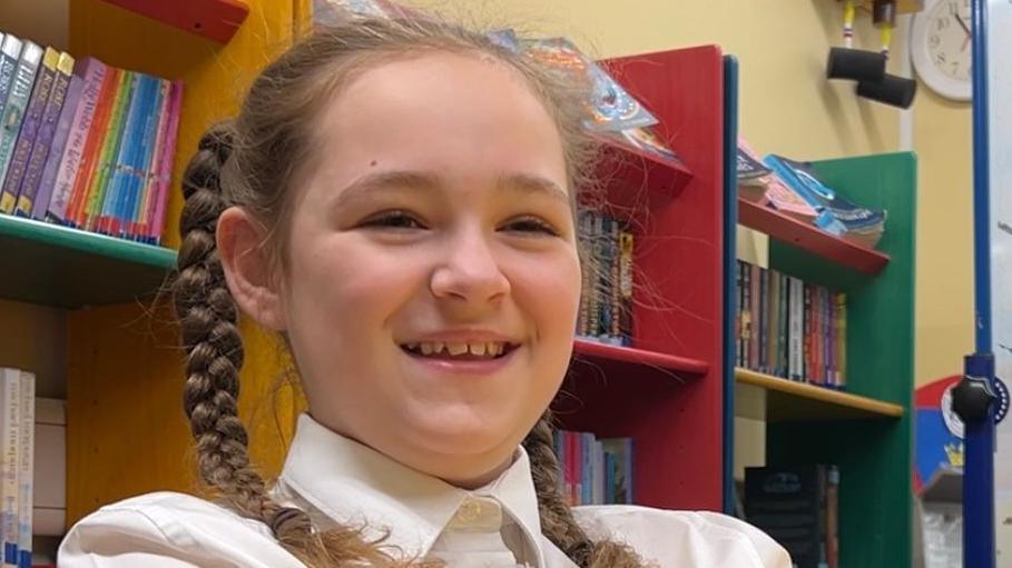 Harper smiles for a photo while at sat in her school's library