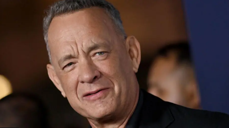 Close-up shot of Tom Hanks looking towards the camera, with a blurred background