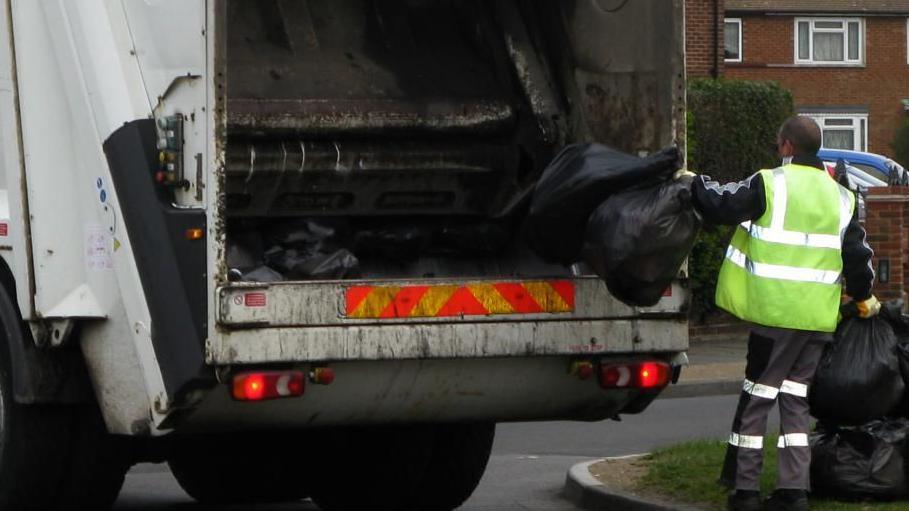 Rubbish being collected and being put into bin lorry.