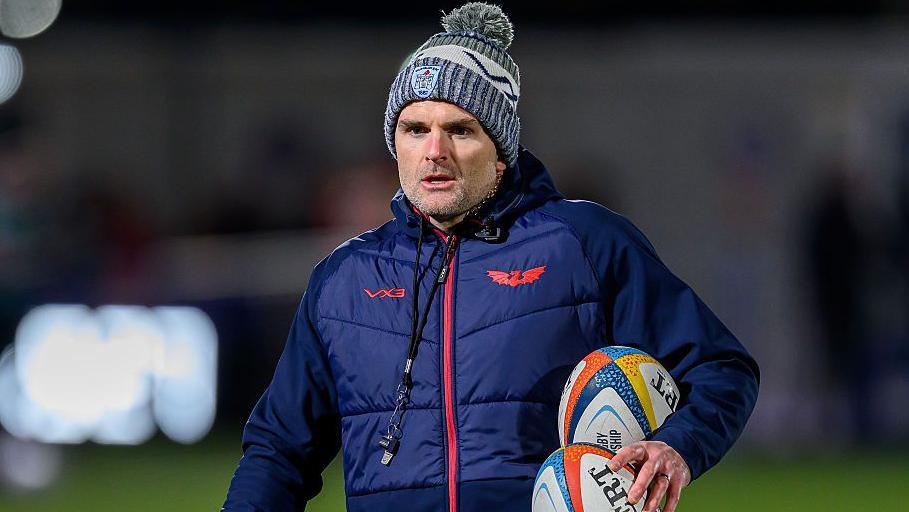 Scarlets defence coach Jared Payne carrying two rugby balls during a warm-up