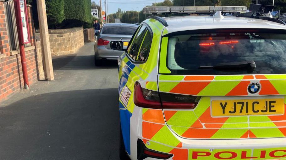 A police car stops an unisured vehicle.