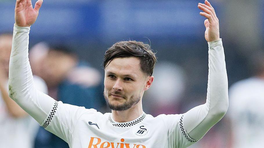 Liam Cullen, while playing for Swansea City, holding his arms up while looking on towards the supporters