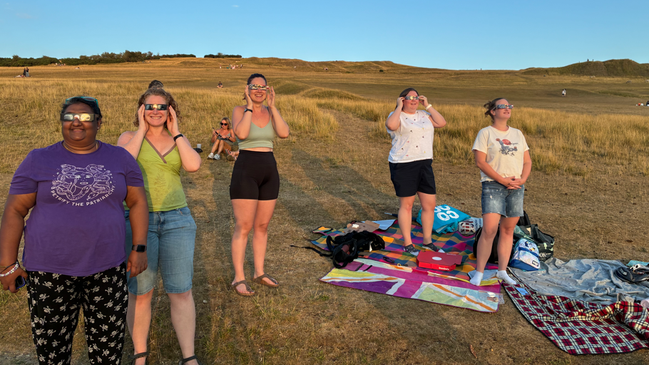 A group of people are standing and looking up at the sun 