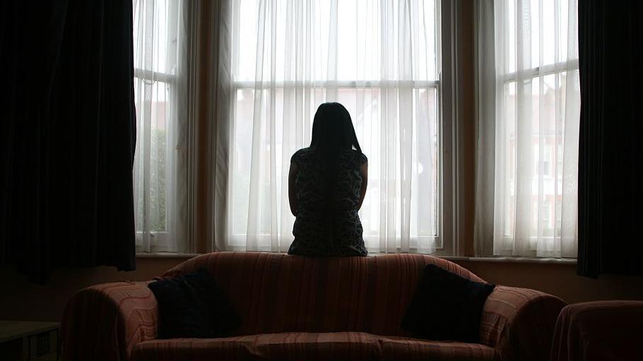 Boireannach na suidhe air beulaibh uinneig