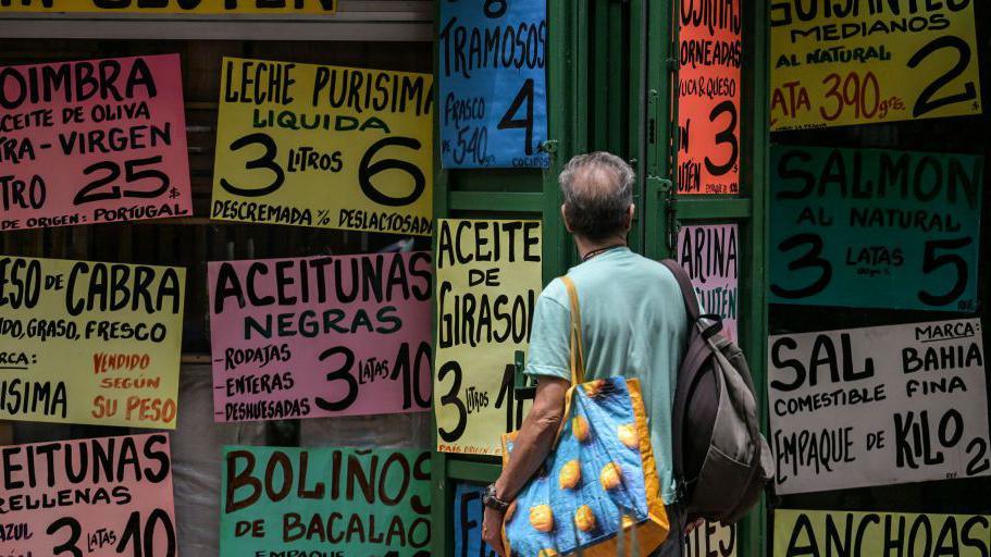 A man looks at food prices outside a Caracas supermarket, 8 May 2024