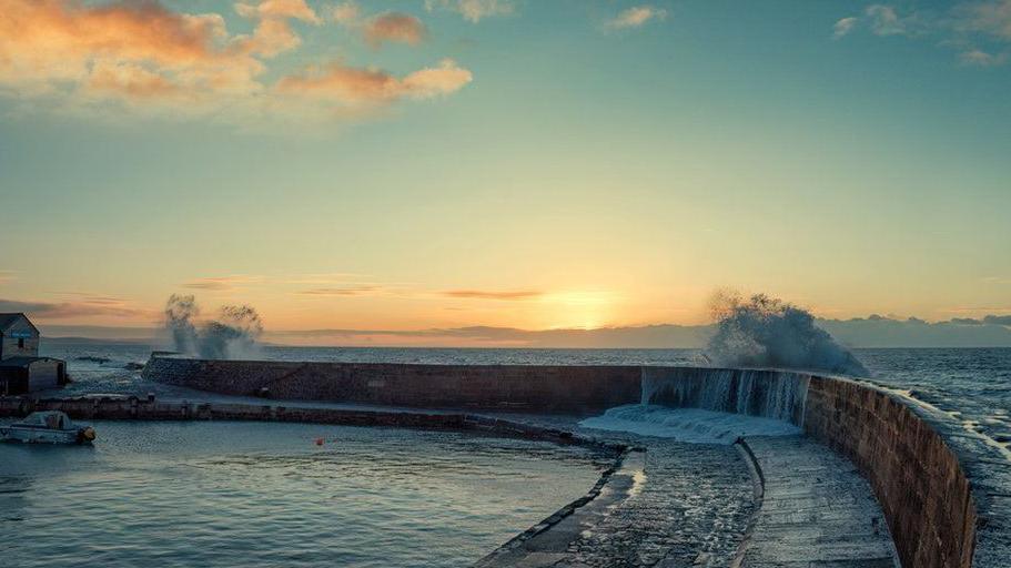 Waves crashing over the Cobb harbour wall