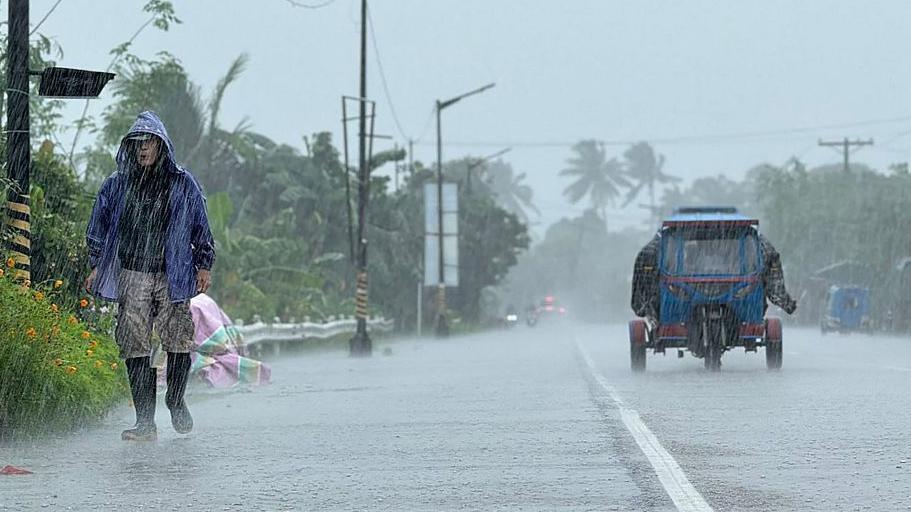 A man walks along a road amid heavy rains ahead of Super Typhoon Ragasa in Lal-lo town, Cagayan province on 22 September
