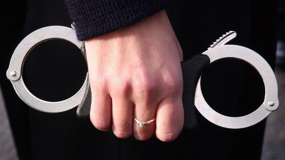 A woman's hand holds a pair of handcuffs