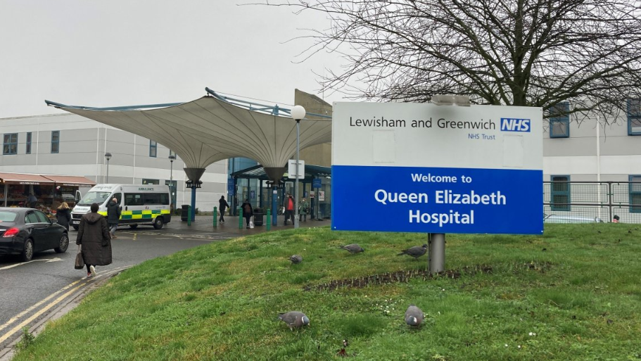 File photo showing the entrance to Queen Elizabeth Hospital with a blue and white NHS sign in front of the building, which features a covered walkway