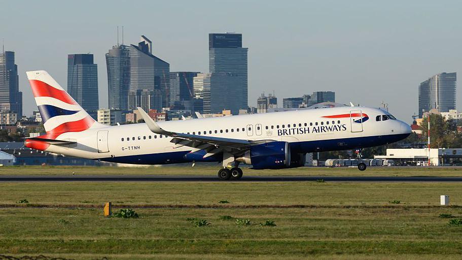 A British Airways Airbus A320 aircraft lands with Warsaw's skyline in the background at the Warsaw Chopin International Airport