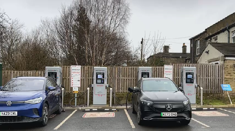 Two cars parked in spaces at an electrical vehicle charging station.