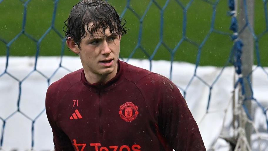 Tom Wooster wearing a red Manchester United warm-up shirt