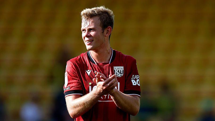 West Bromwich Albion striker Aune Heggebo claps his hands at the end of a match. He is wearing a red away shirt.