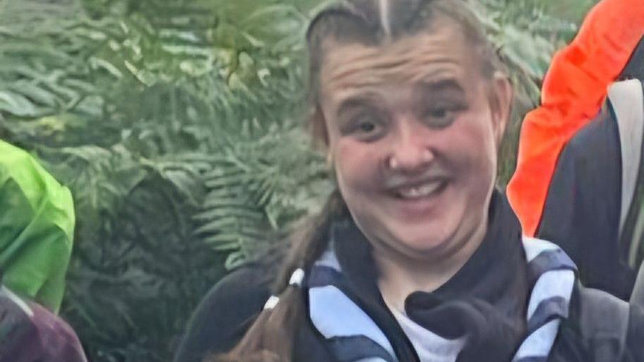 Emily with long brown hair in plaits wearing her Rangers outfit on an expedition.