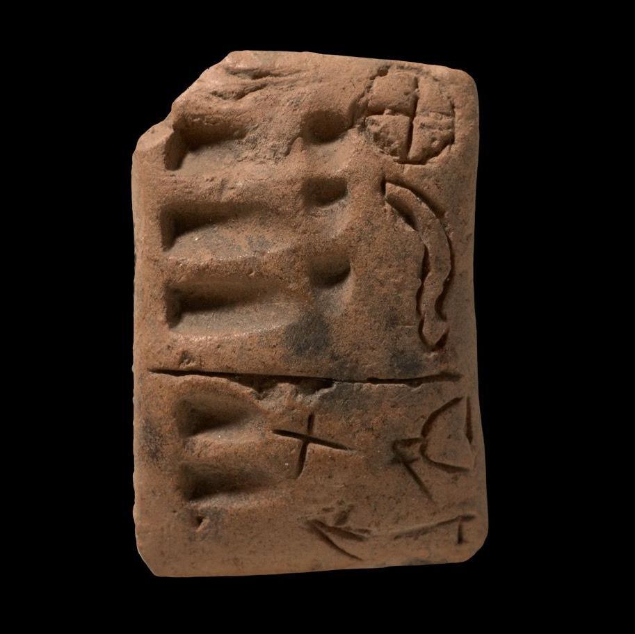 A proto-cuneiform tablet from around 3350 years ago, showing numerical symbols on the left side and a variety of ideograms on the right.