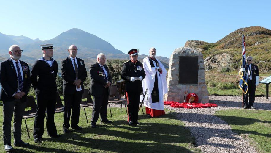 Submariners and relatives of World War Two submariners standing near the memorial