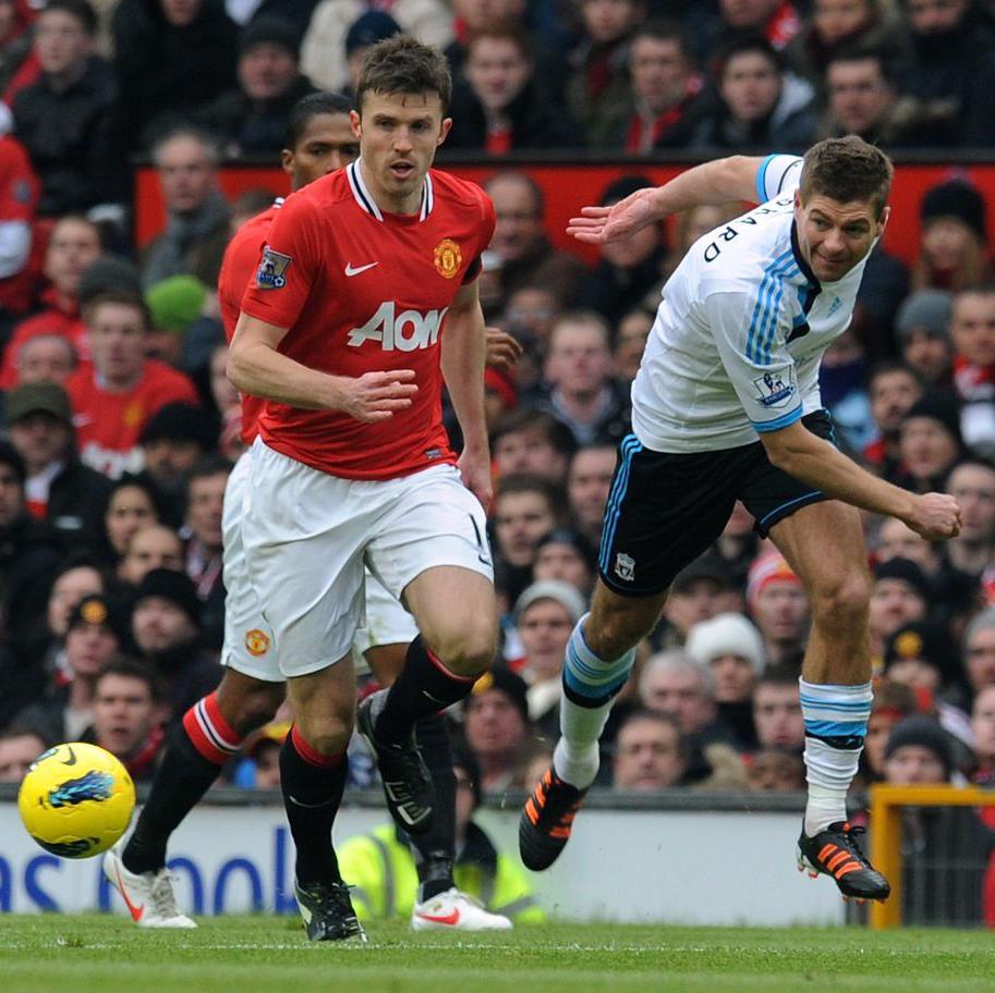 Michael Carrick looks at the ball that has gone past him played by Steven Gerrard during a game between Manchester United and Liverpool in 2012