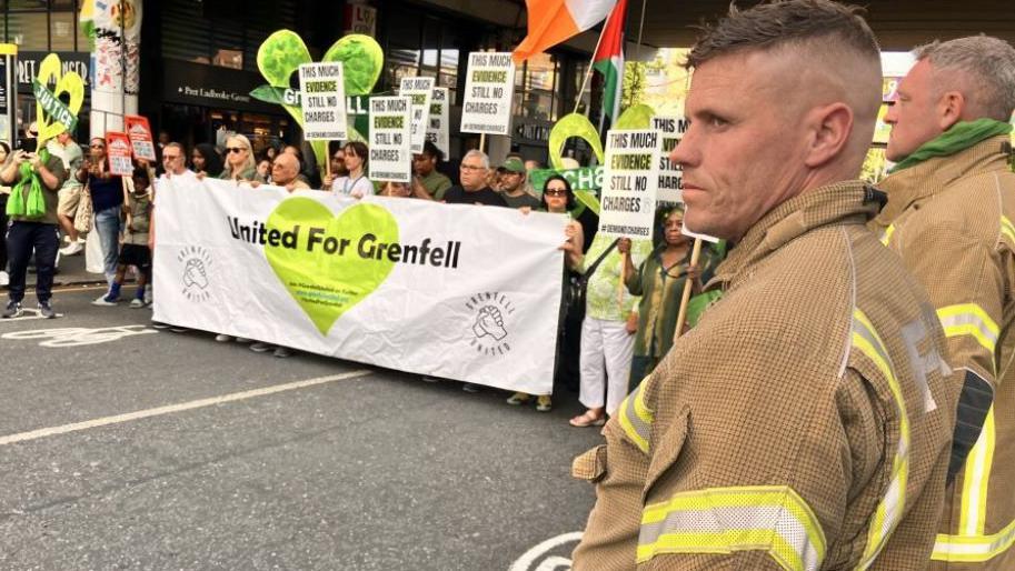 Grenfell campaigners carrying placards and signs march through west London
