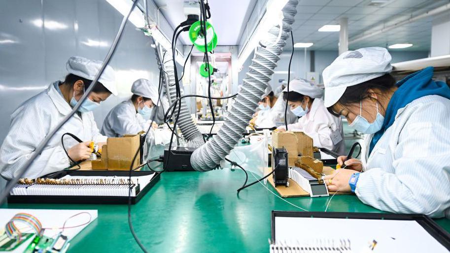 In a semiconductor factory in China, workers on a production line rush to assemble liquid crystal displays and modules. The image shows at least five workers using soldering pens to work on the screens