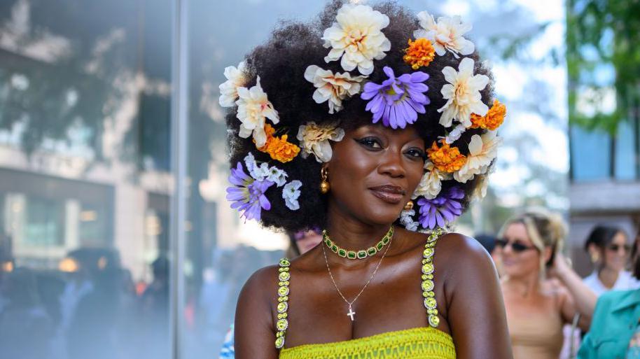 Woman with flowers in her hair and gold jewellery at New York fashion week