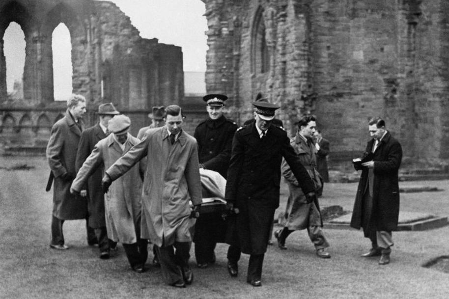 In an old black and white picture from 1951, about seven men carry the Stone of Destiny through the ruins of an abbey.