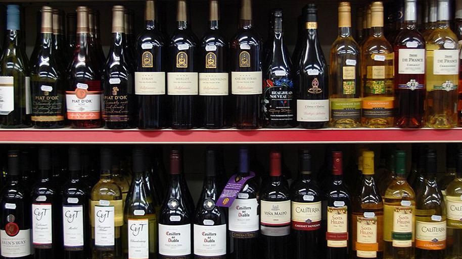 Two shelves in a shop full of bottles of wine