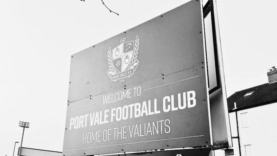 A black and white photo of the Port Vale sign that reads "Welcome to Port Vale Football Club home of the Valiants"