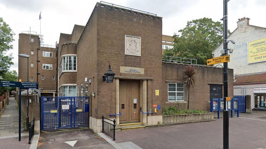 A 1930s style brick Art Deco police station on a suburban London street. It is a large building with one storey at the front and four floors at the rear. 