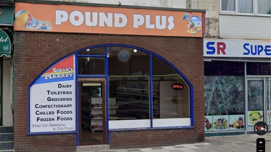 The front of 52 Coronation Street Blackpool which has a Pound Plus sign and Soran's Market sign with a blue surrounding  on a bricked building