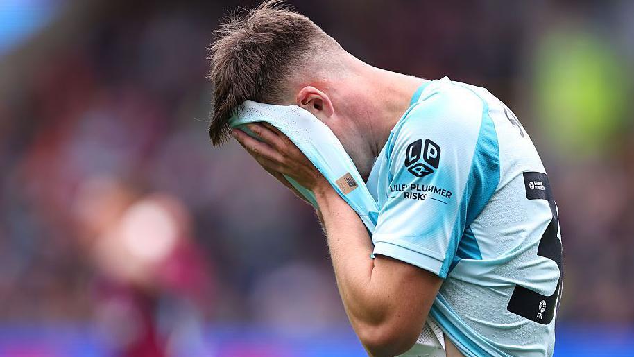 Oliver Scarles of West Ham United pulls his shirt over his face in disappointment
