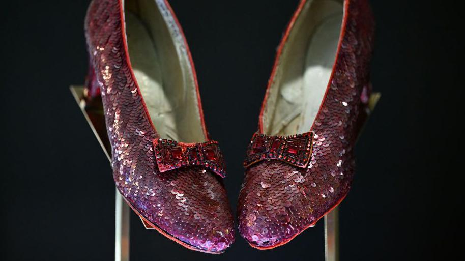 A pair of famous Ruby slippers from the movie 'The Wizard of Oz'. They are displayed on a blackground.