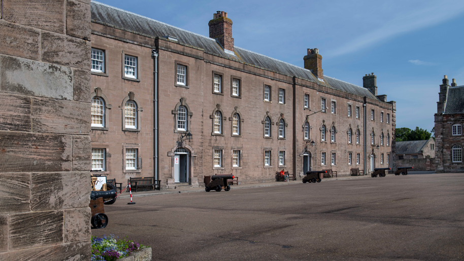 The eighteenth century Berwick barrack, a large continuous building around a parade ground with lots of windows and field guns in front of every door