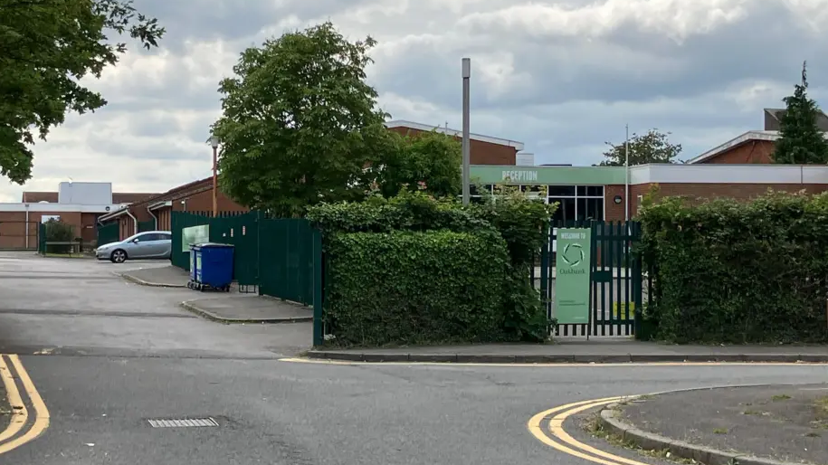 A general view picture of the school's site from a road outside it, including a green sign that says "Welcome to Oakbank".