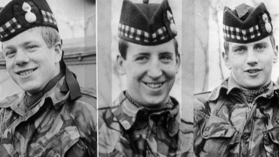 A split black and white photo of the three soldiers who are all smiling as they pose for the camera. All three men are wearing camouflage gear and berets.