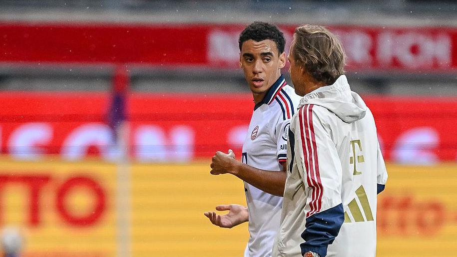 Bayern Munich midfielder Jamal Musiala is guided from the pitch after collapsing in Tuesday's friendly against Heidenheim