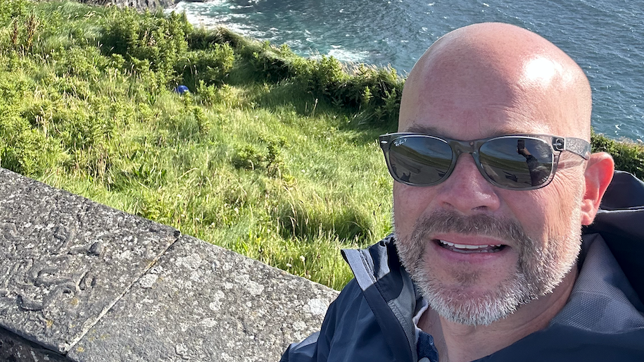 Jason Brown taking a selfie. In the background is the sea and grass.