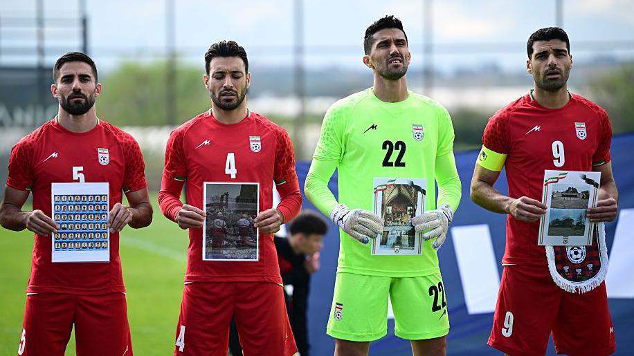 Iran national football team players hold photos of children killed in war as well as damaged hospitals and historical buildings ahead of Tuesday's game against Costa Rica in Turkey