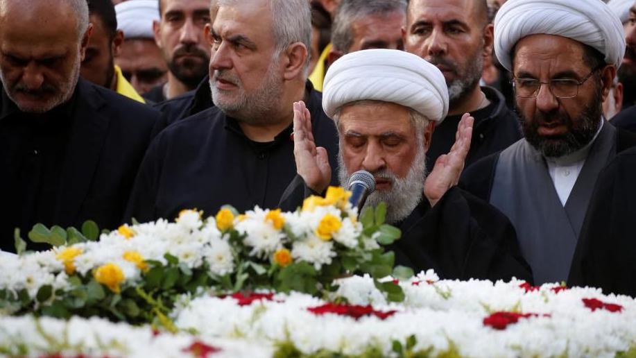 Lebanon's Hezbollah deputy leader Sheikh Naim Qassem, a man with a grey beard, closes his eyes and prays as he leads funeral prayers during the funeral of Hezbollah senior leader Ibrahim Aqil 