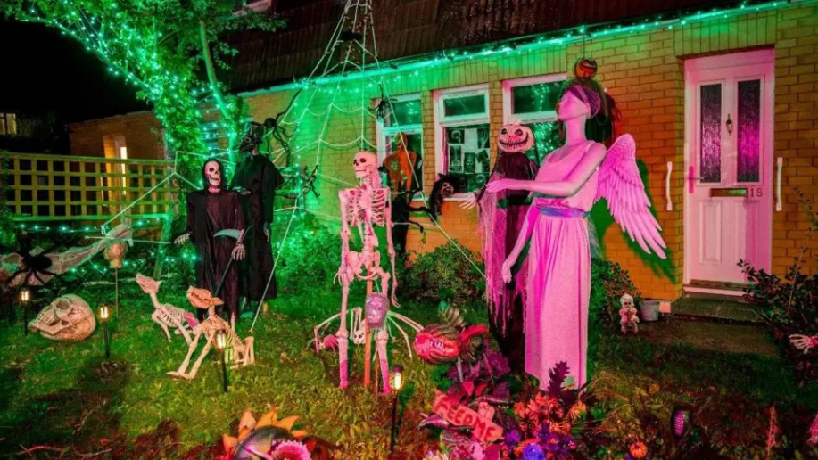 The garden of a yellow brick bungalow is covered with skeletons, a pumpkin-headed figure and a mannequin dressed as an angel.