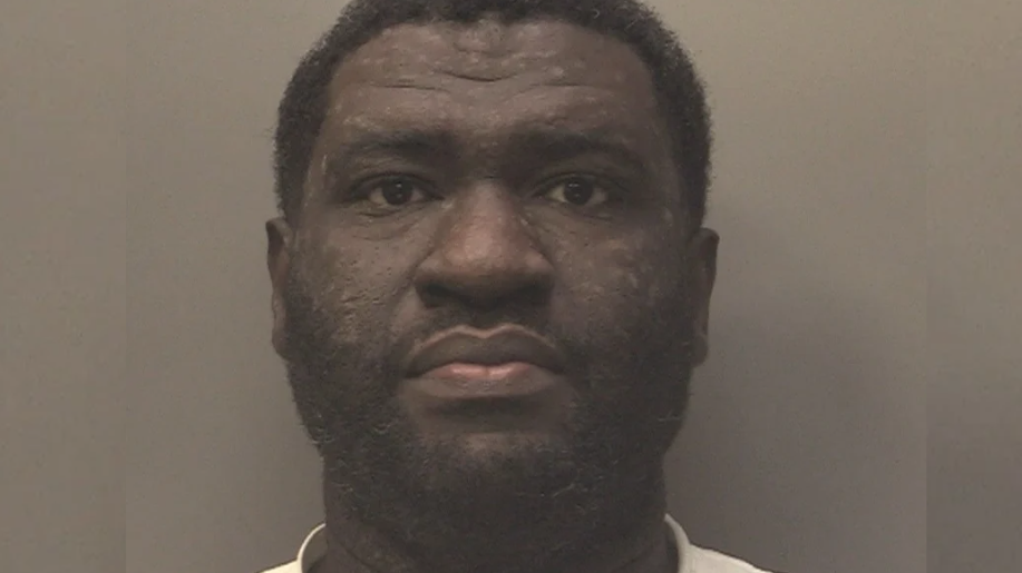 A mug shot of Kwame Yeboah. He has short dark curly hair and is staring into the camera.