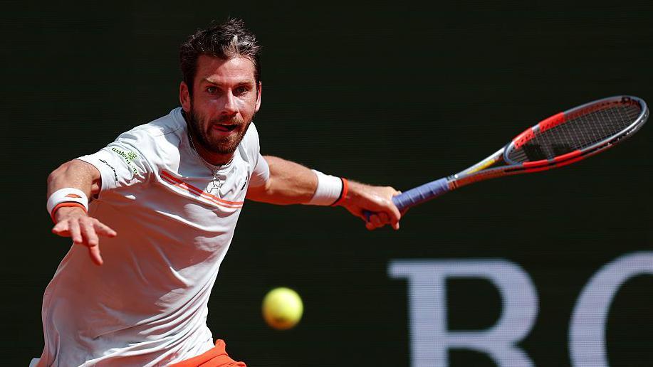 Cameron Norrie, in largely white T-shirt with orange trim, plays a forehand at the Monte Carlo Masters on Sunday