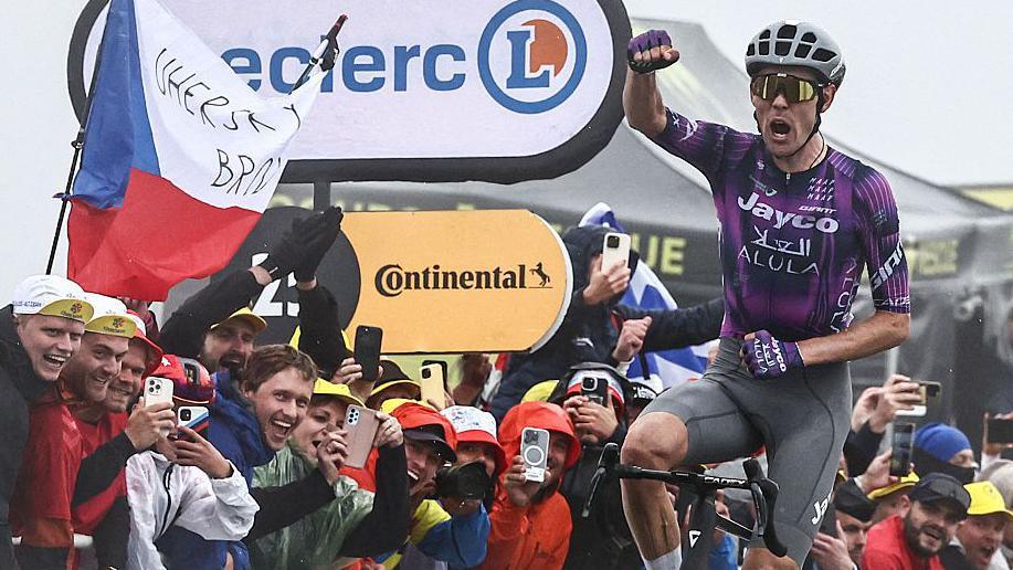 Ben O'Connor raises his fist in triumph after crossing the line at the end of stage 18
