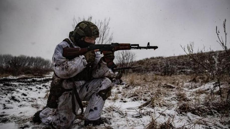 A Ukrainian soldier holds a rifle in the snow