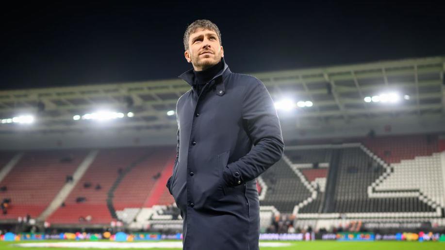 Florent Ghisolfi in a long black coat while working as sporting director at Roma
