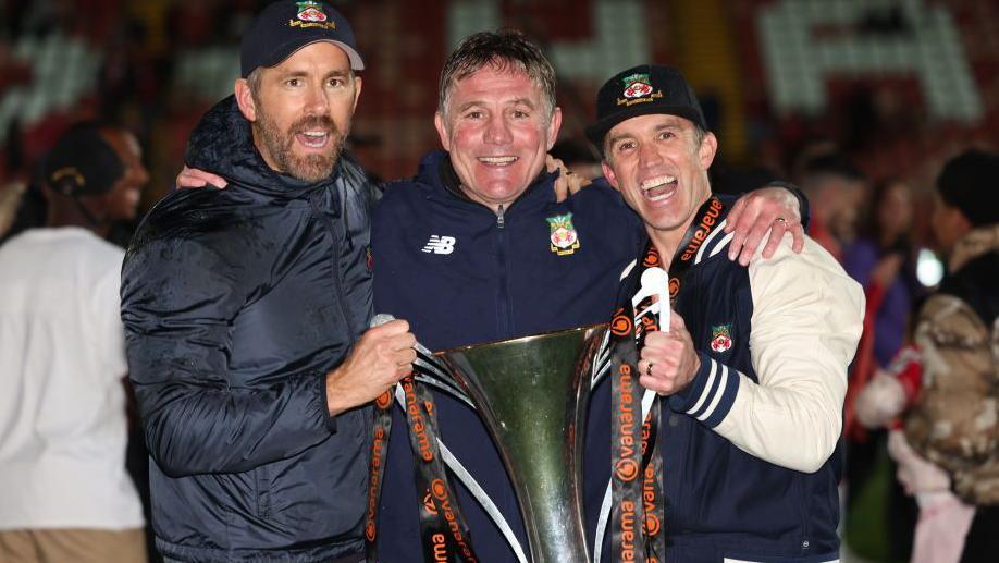 Phil Parkinson (centre) lifting the National League trophy in 2023 with Wrexham co-owners Ryan Reynolds (left) and Rob McElhenney (right)